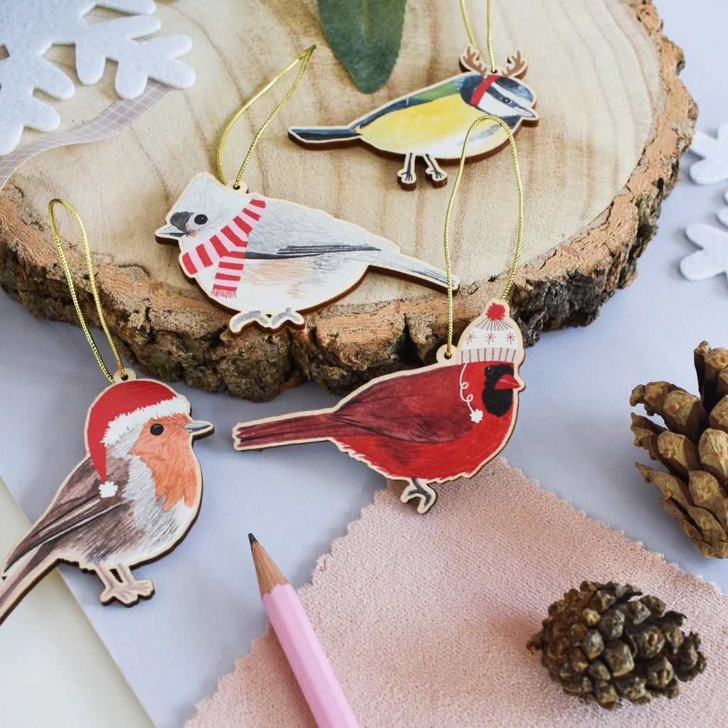 A photograph of 4 wooden bird ornaments in festive attire.